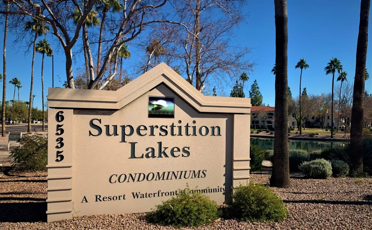 An exterior view featuring the property sign, waterfront vistas, and palm trees, evoking a sense of relaxed community living. The scene suggests opportunities for water activities, community gatherings, and enjoying Arizona’s outdoor lifestyle.