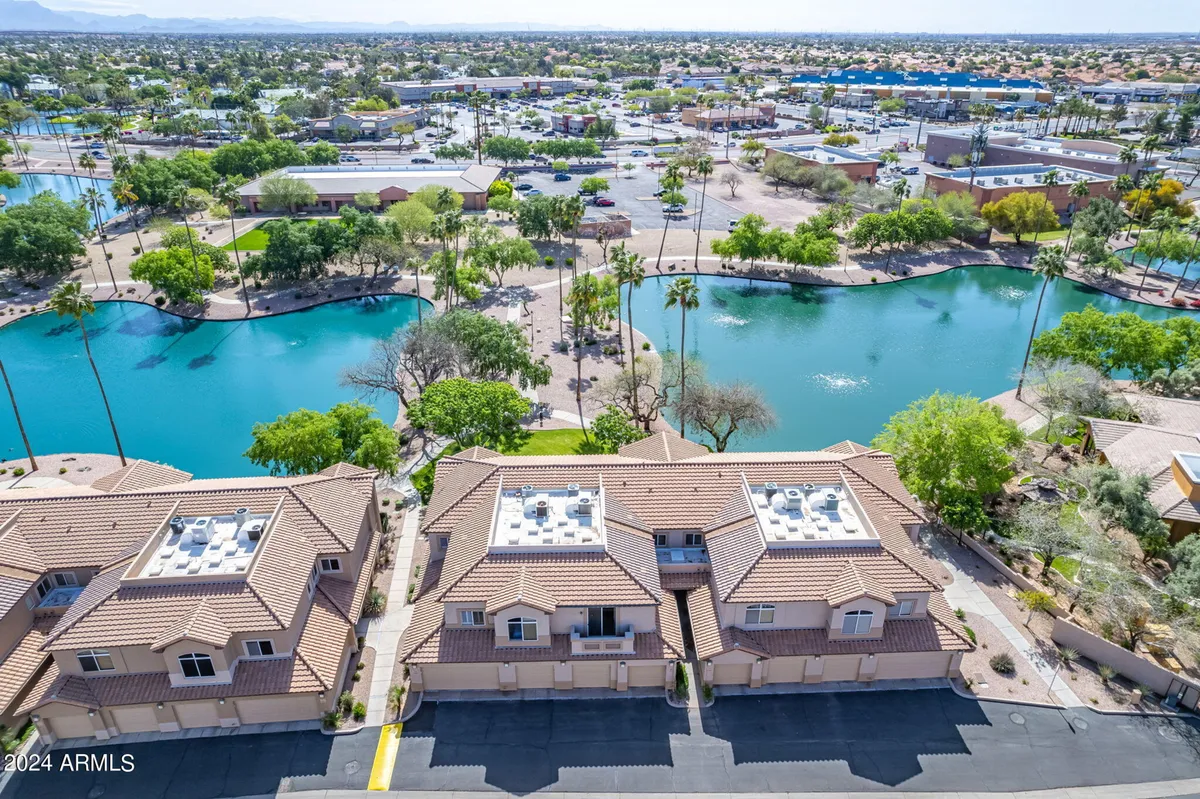 This image captures vibrant blue water bodies flanked by lush greenery, with well-maintained rooftops of the surrounding buildings. Walkways meander along the waterway, inviting residents and visitors to enjoy the tranquil outdoor setting.