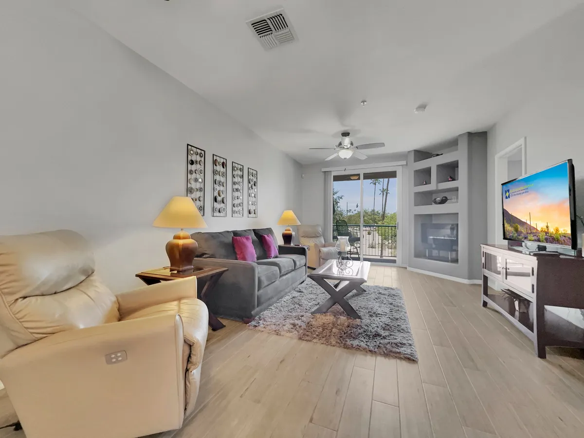 Featuring a comfortable sofa with colorful cushions, a coffee table, television, and a large window with a beautiful view, this living space is bright and welcoming. The arrangement is perfect for both relaxation and socializing, with the view further connecting the indoors with the lush exterior.