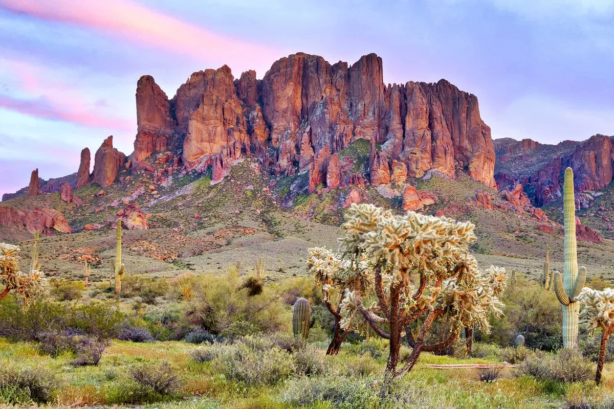 This exterior shot captures dramatic mountain cliffs, lush cacti, and green desert vegetation under a tranquil sky. The mood is calm and reflective, inviting viewers to imagine relaxing or exploring in this picturesque Arizona setting.